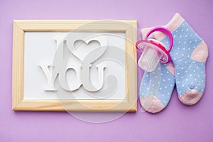 Newborn baby story. Frame with copyspace and children's toys, scissors, baby bottle, nipple, hairbrush on violet background