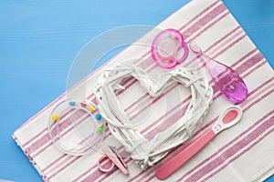 Newborn baby story. Strow heart and children's toys, scissors, baby bottle, nipple, hairbrush on blue background