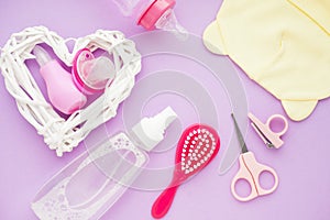 Newborn baby story. Strow heart and children's toys, scissors, baby bottle, nipple, hairbrush on violet background