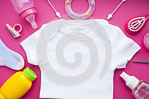 Newborn baby story. T-shirt and children's toys, scissors, baby bottle, nipple, hairbrush on red background