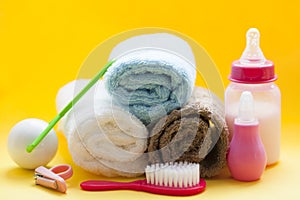 Newborn baby story. Towels and children's toys, scissors, baby bottle, nipple, hairbrush on yellow background