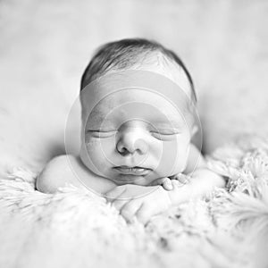 Newborn baby toddler boy or girl lies on hands on the fur and sleeps sweetly. Black and white picture