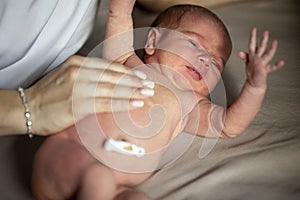 A newborn baby with a treated umbilical cord lies with her mother. Close-up