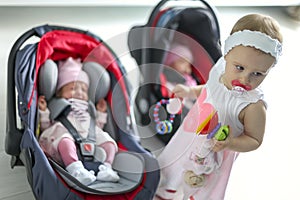 Newborn baby twins girl sitting in a car seat