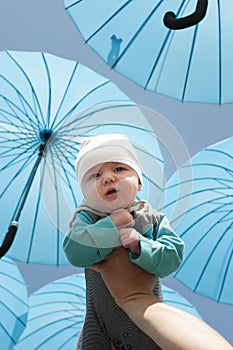 Newborn baby under a blue umbrellas.