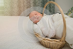 Newborn baby in a white diaper sleeps in a wicker basket on the bed at home in the bedroom. Family concept, home birth