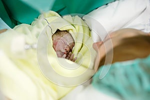 Newborn baby wrapped in blankets after birth. Mother looking for the first time on new born daughter