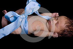 Newborn Baby Wrapped Up in Blue Ribbon with Bow