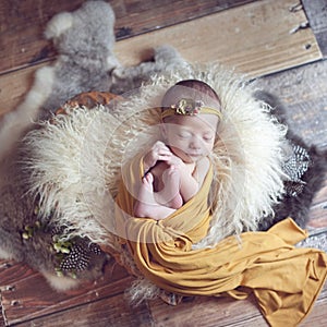 Newborn baby wrapped in wrap on soft fluffy blanket in wooden bowl in the shape of heart beautiful floral headband, with