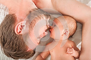 Newborn on the bed with his father close-up. The concept of the relationship of children and parents from birth.