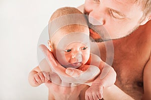 Newborn on the bed with his father close-up. The concept of the relationship of children and parents from birth.