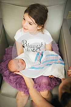 Newborn being held by big sister
