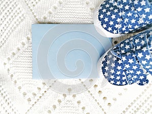 Newborn boy clothes and baby booties on a white knitted background. Greeting card. Place for your text.