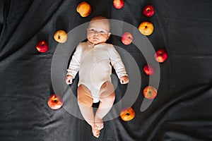 Newborn boy lying with apples. A small child in a white bodysuit