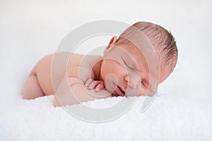 Newborn boy resting chin on arms