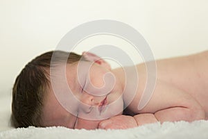 Newborn caucasian male baby sleeping on white blanket