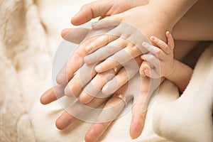 Newborn child hand. Closeup of baby hand into parents hands. Family, maternity and birth concept.