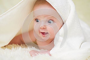 Newborn child relaxing in bed. Six months old baby with a towel after taking a bath, in bed at home