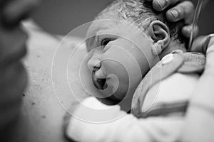 Newborn child seconds and minutes after birth. Baby being born via Caesarean Section. Doctor hands with new born girl