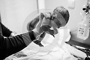 Newborn child seconds and minutes after birth. Doctor hands with new born baby. Medical check up of health and reflexes