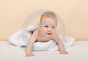 Newborn child smiling. Baby boy wearing white towel in white bedroom