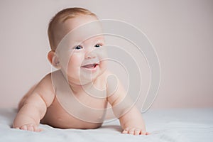 Newborn child wearing a diaper in white sunny bedroom. Newborn child relaxing in bed. Beautiful girl lies a happy smile, great