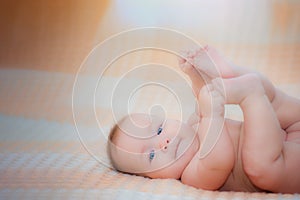 Newborn child wearing a diaper in white sunny bedroom. Newborn child relaxing in bed. Beautiful girl lies a happy smile, great