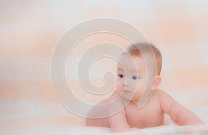 Newborn child wearing a diaper in white sunny bedroom. Newborn child relaxing in bed. Beautiful girl lies a happy smile, great