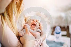 Newborn cries in arms of his mother