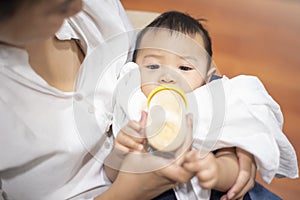 Newborn cute baby is drinking milk from bottle by mom