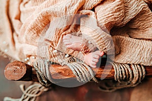 A newborn cute baby sleeping in a vintage wooden cradle with open foot and toes.