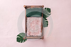 Newborn digital background - brown wooden bed on pink background with monstera plant leaves, green pillow and pink faux fur