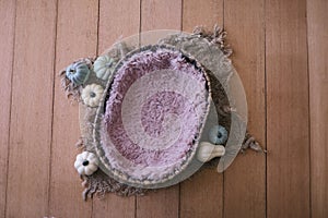 Newborn digital background - natural oval woven bowl with pink faux fur layer, jute and colorful pumpkins on wooden background,