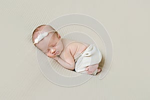 Newborn girl in hairband sleeping on her side photo
