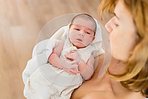 Newborn girl in loving arms of her mother