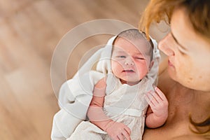 Newborn girl in loving arms of her mother