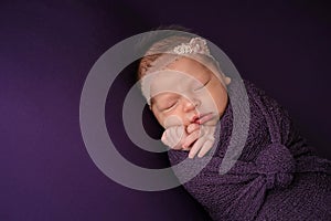 Newborn Girl Sleeping in a Purple Swaddle