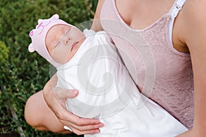 Newborn girl sleeps sweetly in mom`s arms