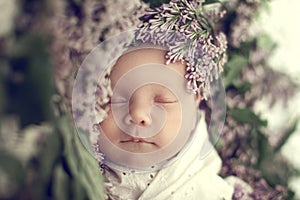 Newborn girl wrapped in white, sleeping peacefully