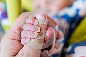 Newborn holding fathers thumb