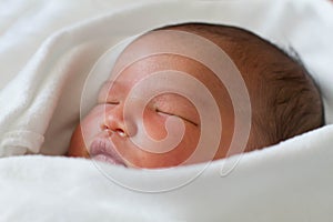 Newborn infant baby girl sleeping in bed