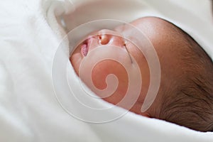 Newborn infant baby girl sleeping in bed