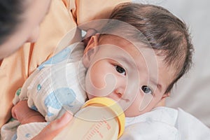 Newborn infant baby have milk from bottle with feeding from mother