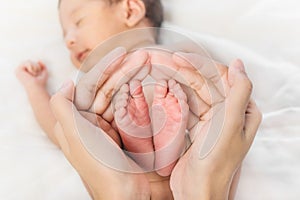 Newborn infant baby holding in hand of mother