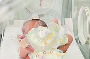 Newborn innocent baby sleeping in an incubator