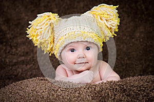 Newborn in knitted winter hat on a beige background.