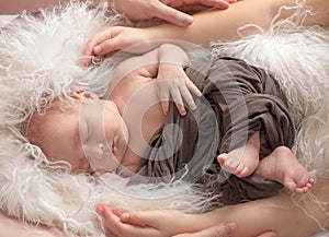 Newborn little boy sleeping surrounded by family, Hands of mom and dad hug a newborn baby, loving parents, long-awaited baby.