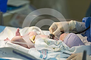 Newborn male baby being checked with stethoscope