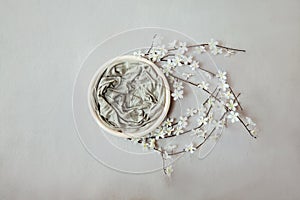 Newborn neutral spring background - round white bowl with white flowers and branches wreath on light beige backdrop