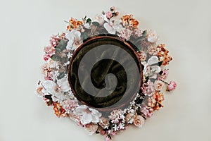 Newborn photography background - floral wreath on white background with wooden bowl and green knitted center. Newborn girl